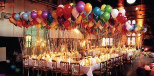 Two sets of tables arranged in a horseshoe and sitting approximately 36 people, with a massive amount of balloons tied to each chair.