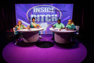 Four people are sat at two round desks as if on a TV talk show. Behind them is a banner with 'Inside Bitch'