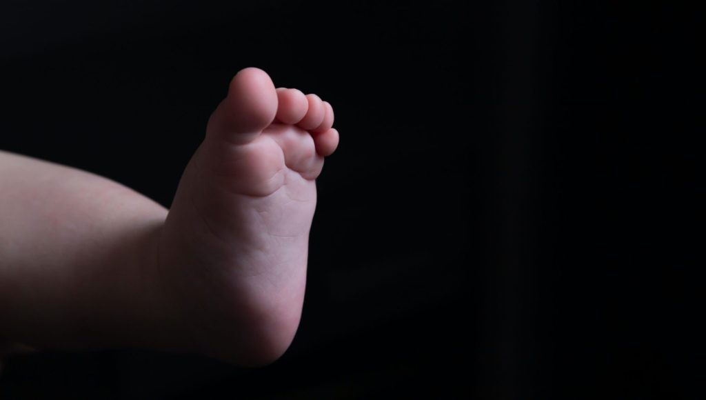 A baby's foot with a black background